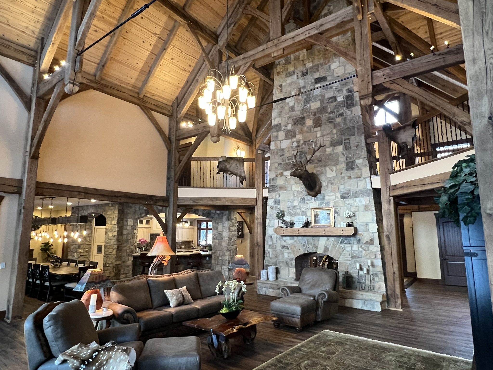 Timber-frame great room with stone fireplace and chandelier